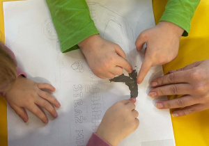 Dzieci wyklejają plasteliną pojazd straży miejskiej