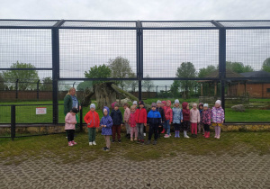 Dzieci stoją przed wolierą w zoo