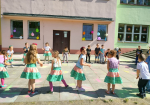 Dzieci tańczą w kole na dziedzińcu placówki