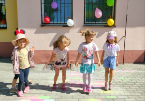 Dziewczynki tańczą przed budynkiem przedszkola