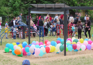 Widok na balony w piaskownicy i rodziców z dziećmi w tle