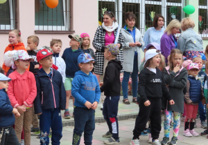 Dzieci i nauczycielki stoją na dziedzińcu przedszkola