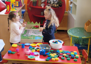 Dzieci stoją w pobliżu stołu i rozmawiają.