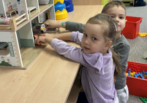 Dzieci bawią się domkiem dla lalek