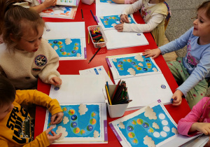 Dzieci siedzą przy stołach i podejmują próby rozwiązywania zadań w kartach pracy.