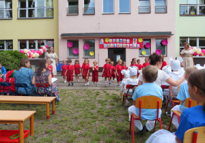 Żabki w czerwono czarnych strojach prezentują przygotowany taniec.