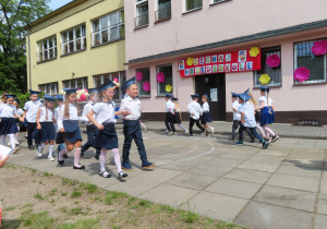 Najstarsze przedszkolaki ubrane na galowo tańczą poloneza.