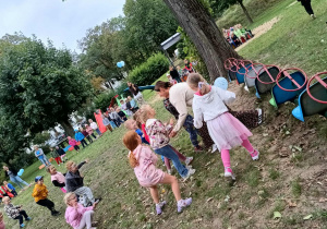 Dzieci bawią się z panią w ogrodzie przedszkolnym.