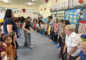 Dzieci wraz z rodzicami i paniami wykonują taniec w kole.