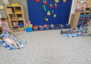 Dzieci przeciągają się po dywanie na kocach.