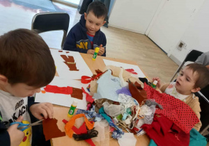 Chłopcy siedzą przy stole i wycinają elementy do portretu.