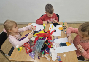 Dzieci wycinają kawałki materiału.