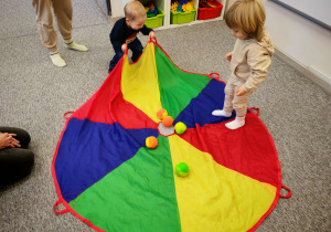 Chłopcy bawią się z wykorzystaniemkolorowej chusty animacyjnej.