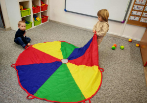 Chłopcy bawią się z wykorzystaniemkolorowej chusty animacyjnej.