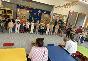 Przedszkolaki prezentują młodszym gościom inscenizacje wiersza "Na straganie"