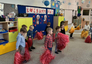 Dzieci z grupy Żabek wykonują taniec z czerwonymi pomponami.