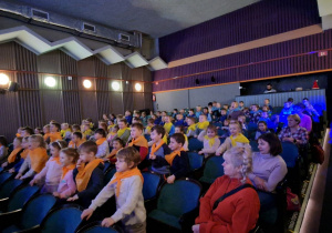 Dzieci siadają w fotelach i oczekują na rozpoczęcie przedstawienia.