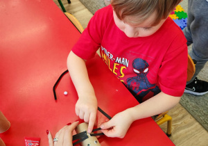 Chłopiec dokleja wąsy z pasków czarnego papieru.