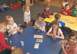 Dzieci siedzą przy niebieskim stole i tworzą koty.